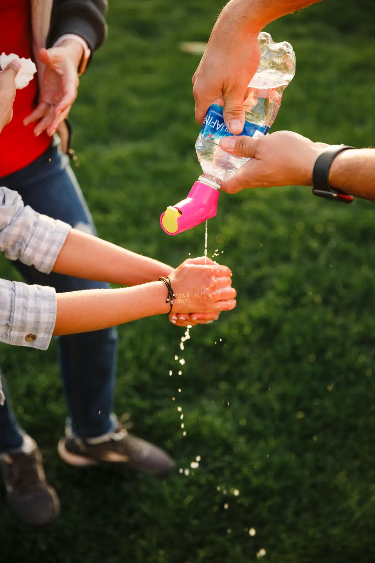 Rinsing hands at the park with a pink Suds2Go Cap on a water bottle